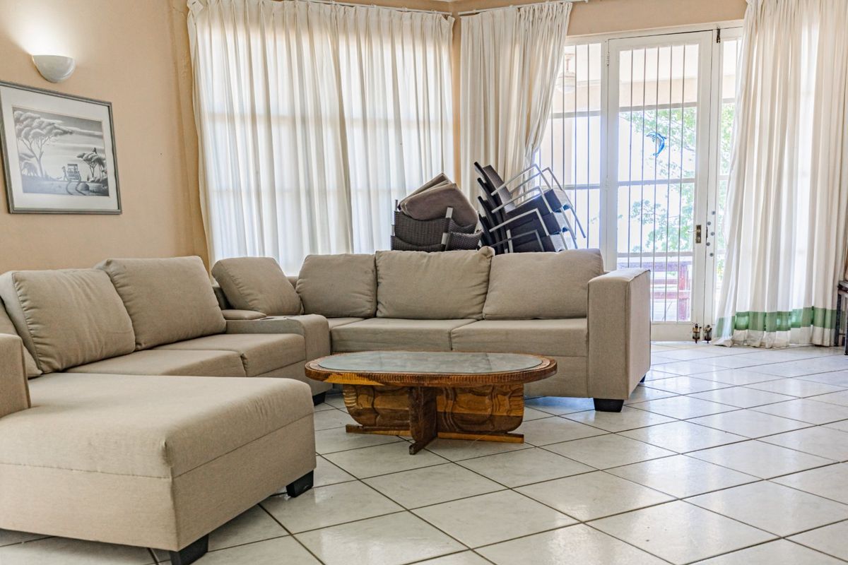 A living room featuring tiled flooring, wall sconce lighting, and direct access to the outdoor area through a security gate.