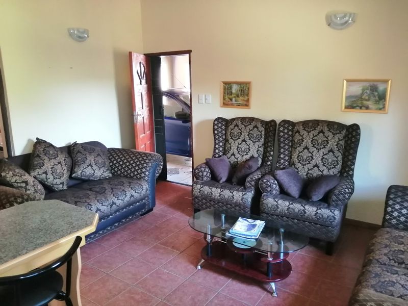 A living room area featuring tiled flooring and wall-mounted lighting, with direct access to an adjacent garage space.