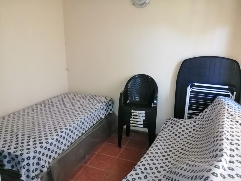 A simple bedroom featuring tiled flooring and plain walls, offering a functional space that could be enhanced with modern decor and finishes.