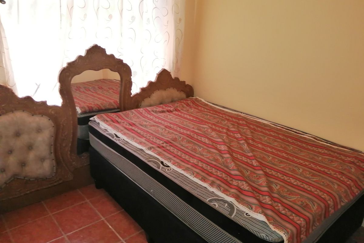 A bedroom featuring tiled flooring and neutral wall finishes, providing a functional space for rest.
