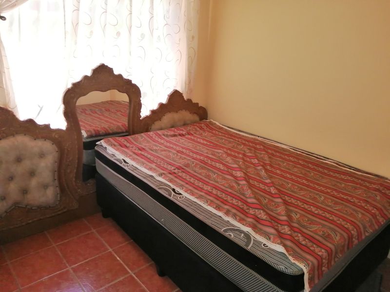 A bedroom featuring tiled flooring and neutral wall finishes, providing a functional space for rest.