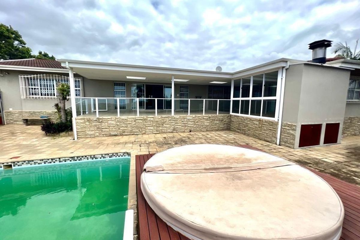 Rear exterior view featuring a covered patio, swimming pool, and a raised deck area with a spa cover.
