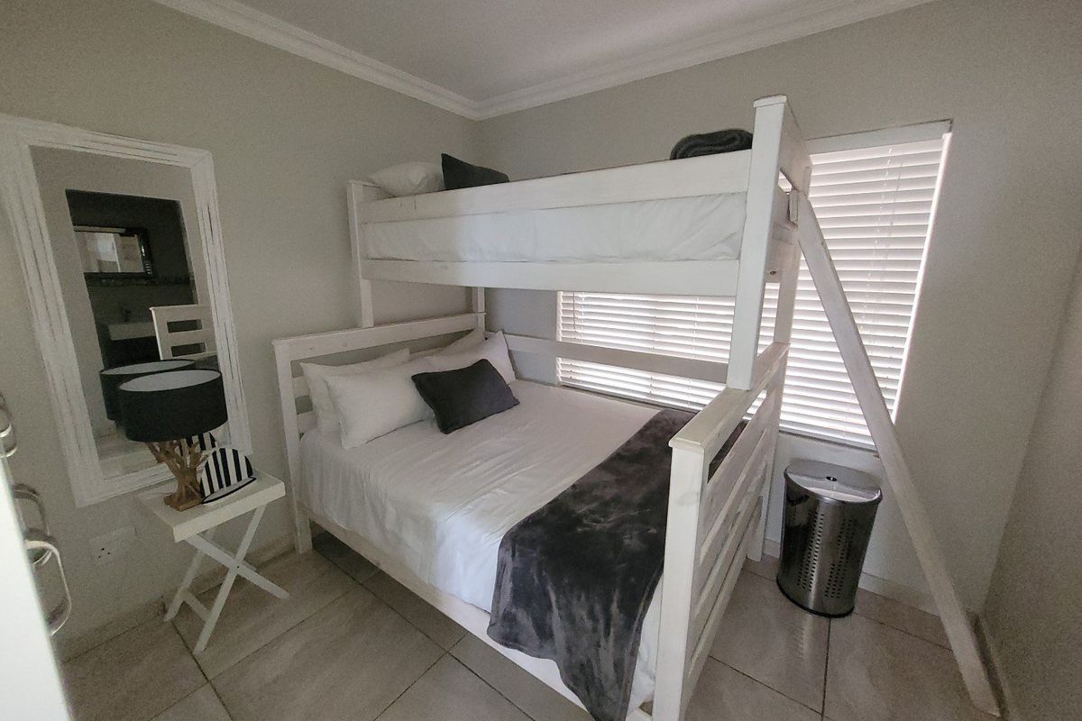 A compact bedroom featuring tiled flooring, neutral wall finishes, and venetian blinds, providing a functional sleeping space.
