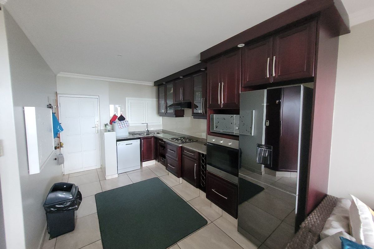A functional kitchen featuring dark wood cabinetry, granite countertops, built-in oven, extractor fan, and tiled flooring, offering a practical layout for daily use.