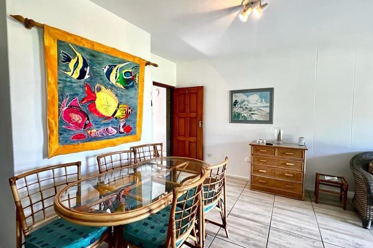 A living and dining area featuring tiled flooring, neutral walls, and a wooden door, providing a functional and open living space.