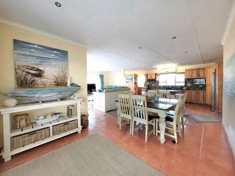 Spacious open-plan living, dining, and kitchen area featuring tiled floors, recessed lighting, and traditional wooden cabinetry, offering a functional and connected layout.