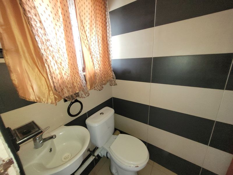 A compact bathroom featuring a white ceramic basin with chrome tapware and a dual-flush toilet, finished with bold horizontal striped wall tiles.