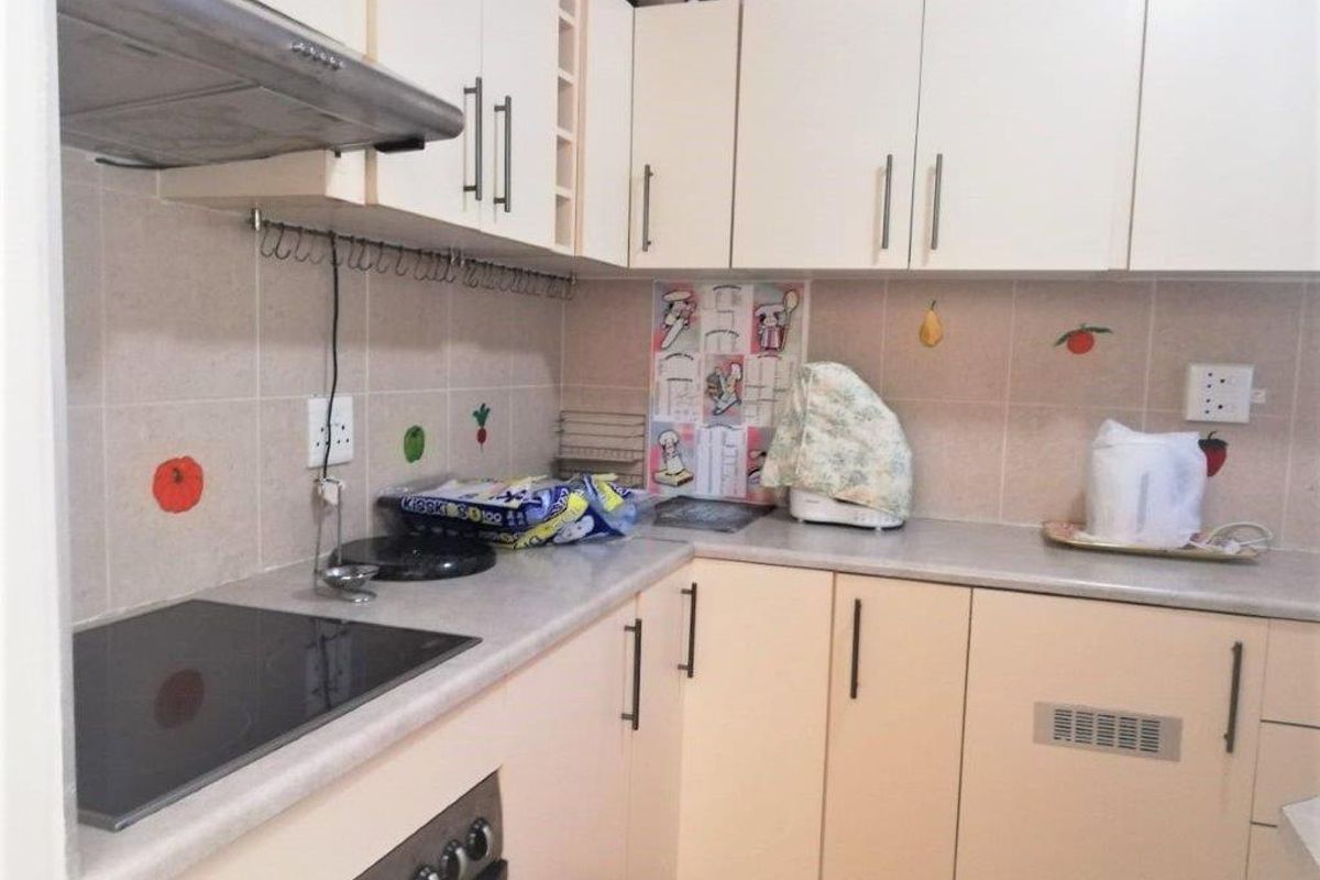 A functional kitchen featuring built-in cabinetry, laminate countertops, an electric hob, an integrated oven, and a tiled backsplash.