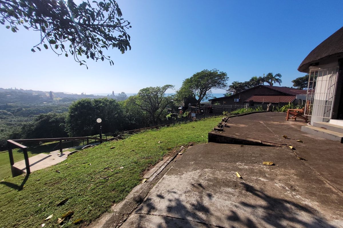 Rear exterior view of the townhouse featuring a concrete patio, lawn area, and scenic coastal landscape views.