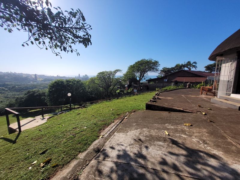 Rear exterior view of the townhouse featuring a concrete patio, lawn area, and scenic coastal landscape views.