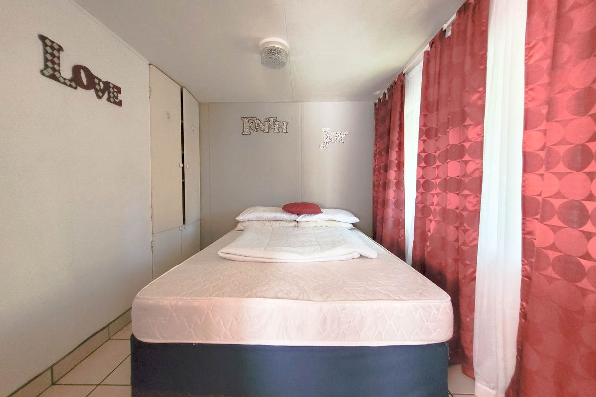 A functional bedroom featuring tiled flooring and built-in storage cupboards, offering a neutral base for potential interior updates.