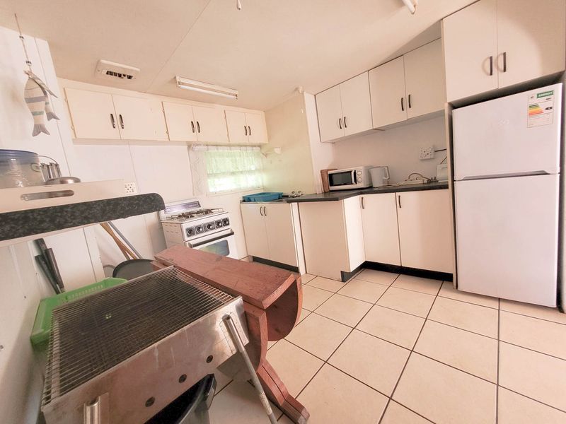 A functional kitchen featuring white built-in cabinetry, tiled flooring, and a freestanding stove, offering a practical layout with potential for modern updates.
