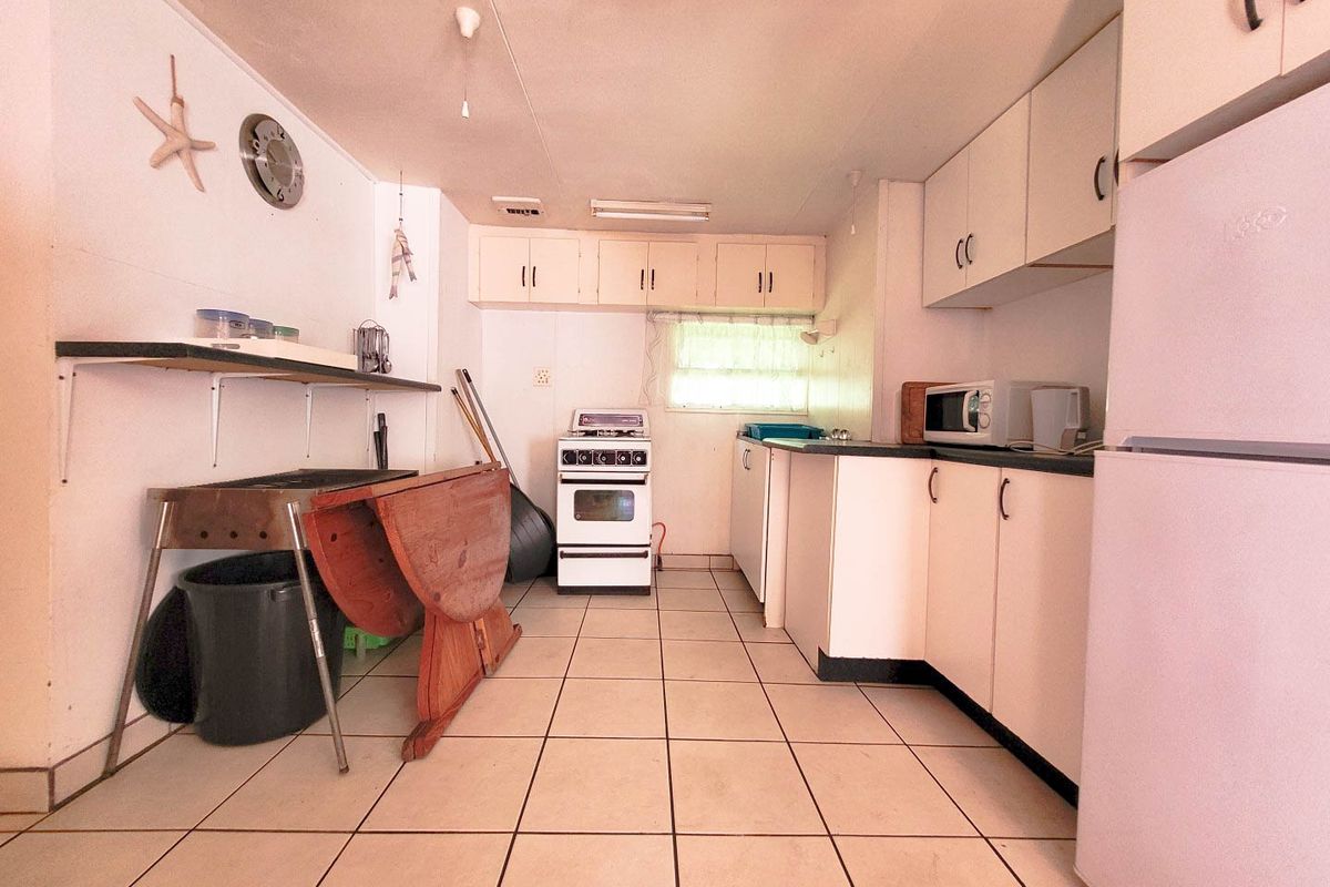 A functional kitchen featuring white cabinetry, tiled flooring, and a freestanding stove, offering potential for modernization and cosmetic updates.