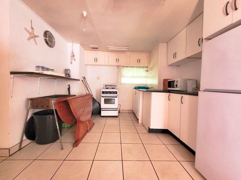 A functional kitchen featuring white cabinetry, tiled flooring, and a freestanding stove, offering potential for modernization and cosmetic updates.