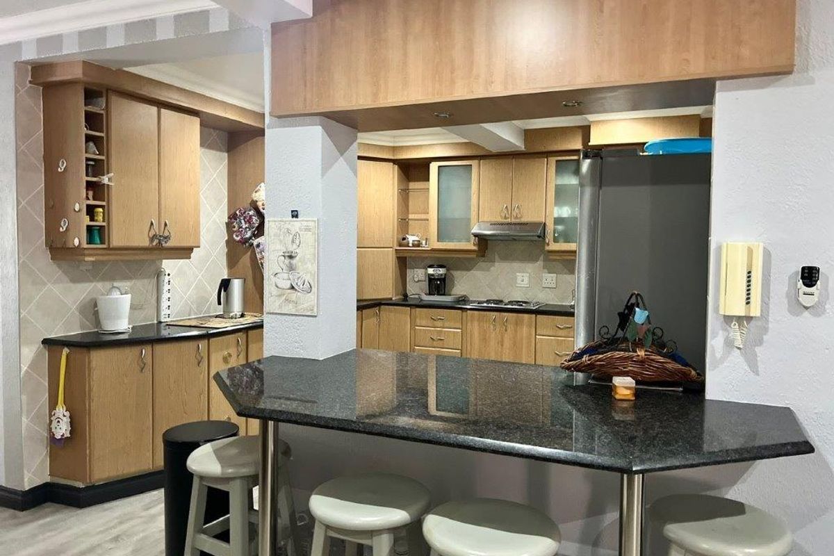 A functional kitchen featuring wooden cabinetry, granite countertops, a breakfast bar, and a tiled backsplash, offering a practical layout for daily use.