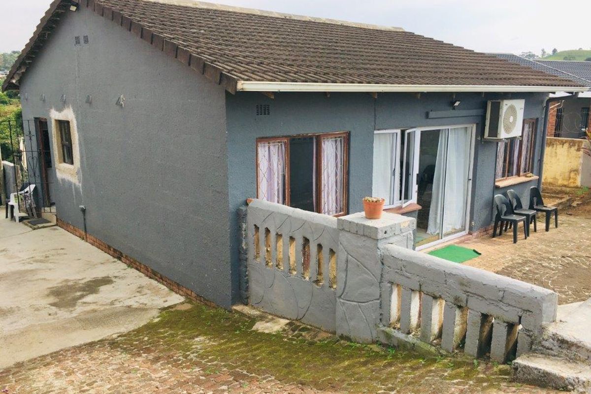 Rear view of a detached house featuring a concrete tile roof, sliding glass doors, and a paved patio area with a concrete balustrade.