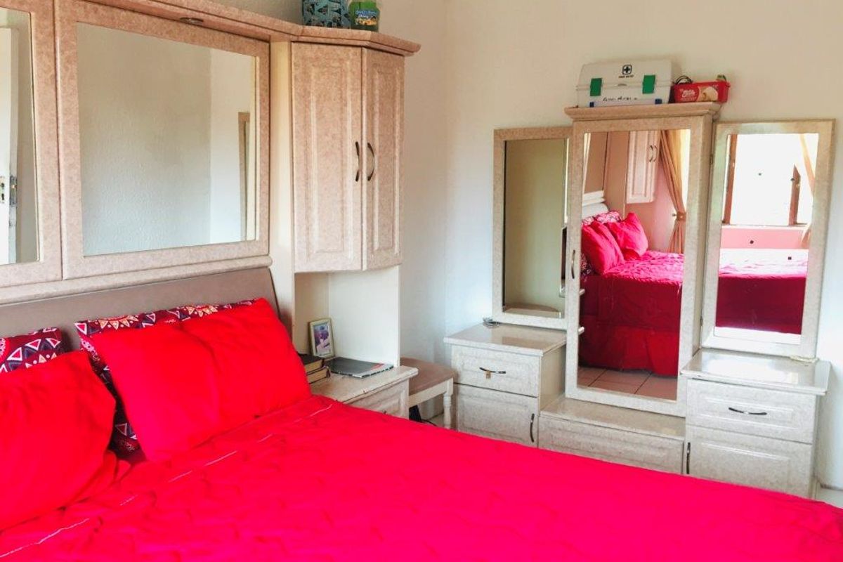 A bedroom featuring built-in cabinetry and a matching vanity unit with integrated mirrors, providing ample storage and functional space.