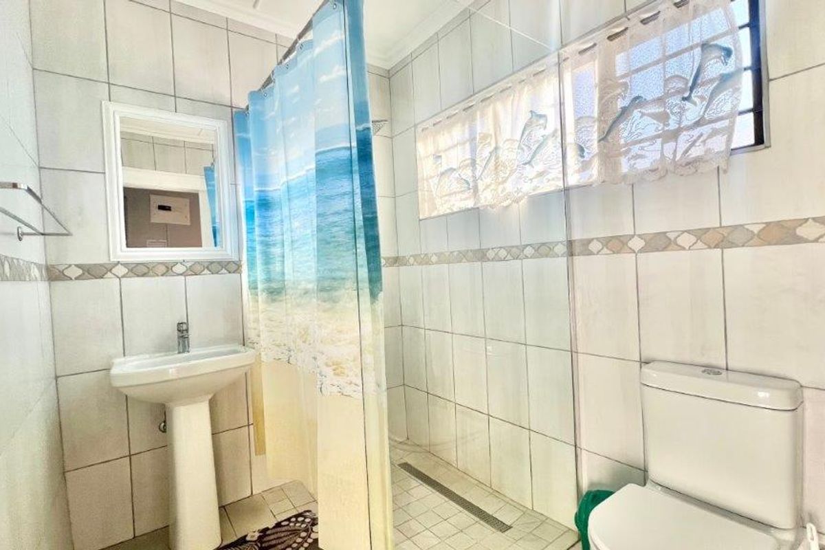A functional bathroom featuring a pedestal basin, a walk-in shower with tiled finishes, and a standard toilet.