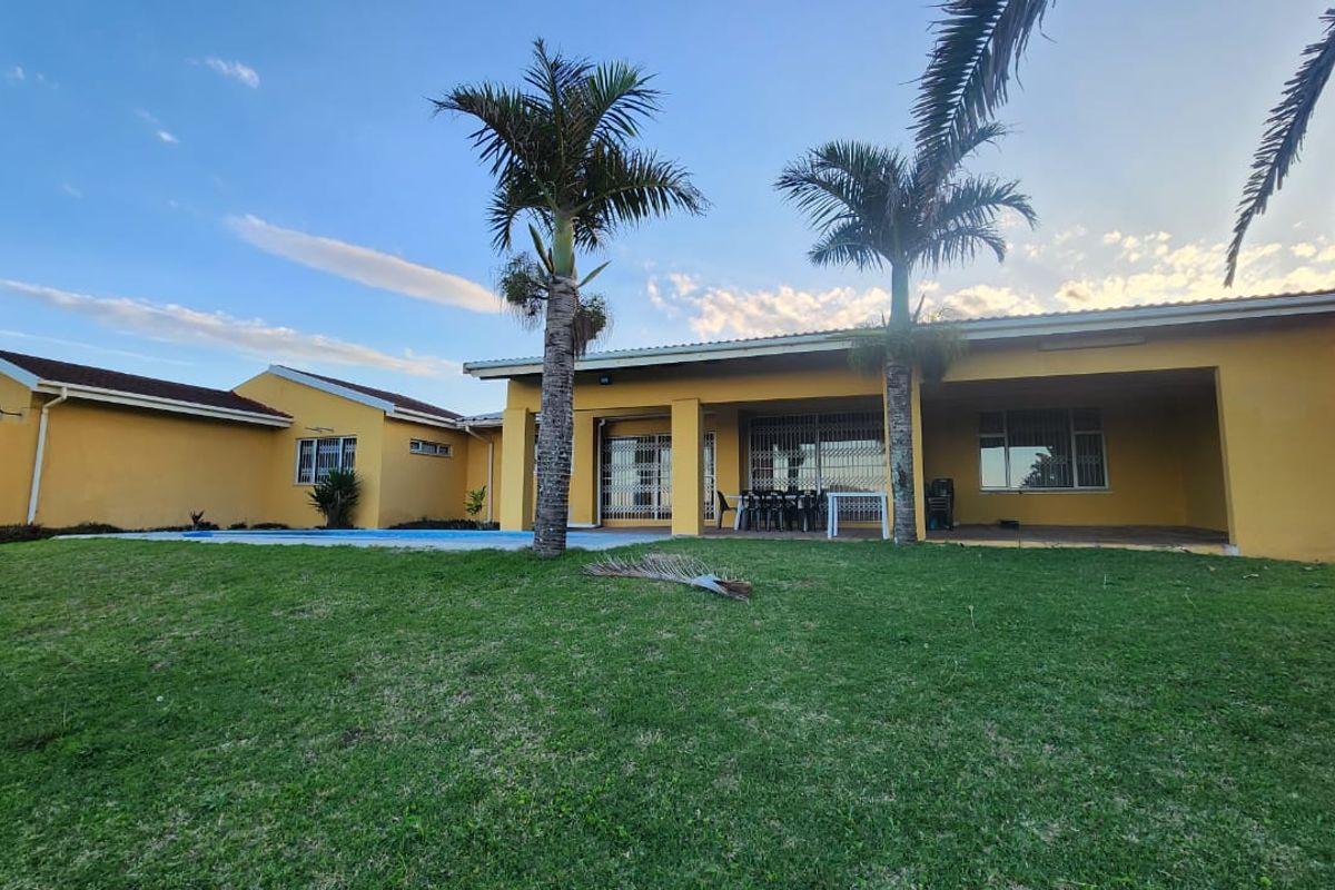 Rear view of the house featuring a covered patio, swimming pool, and a spacious lawn area.