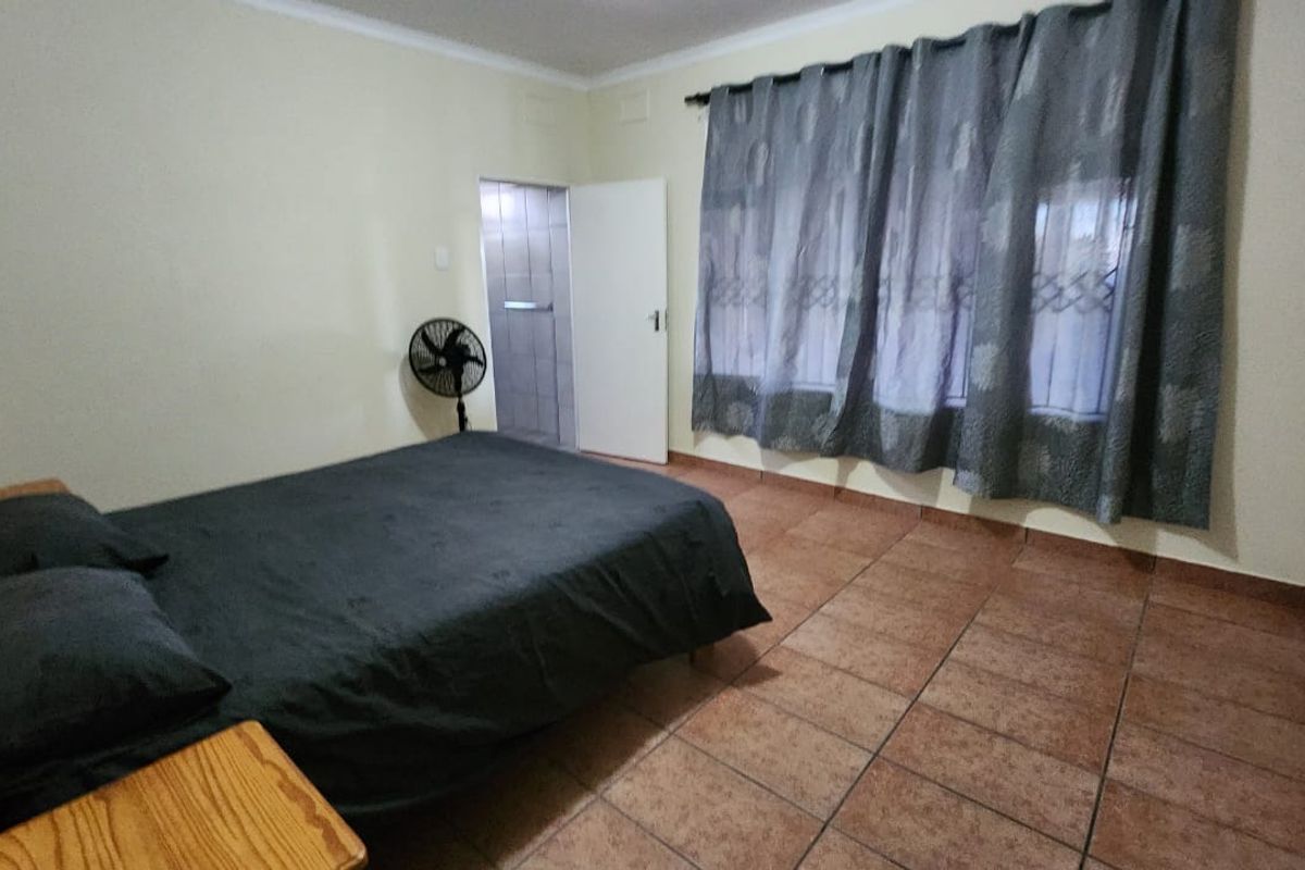 A spacious bedroom featuring tiled flooring and a built-in cupboard, providing a functional and neutral living space.