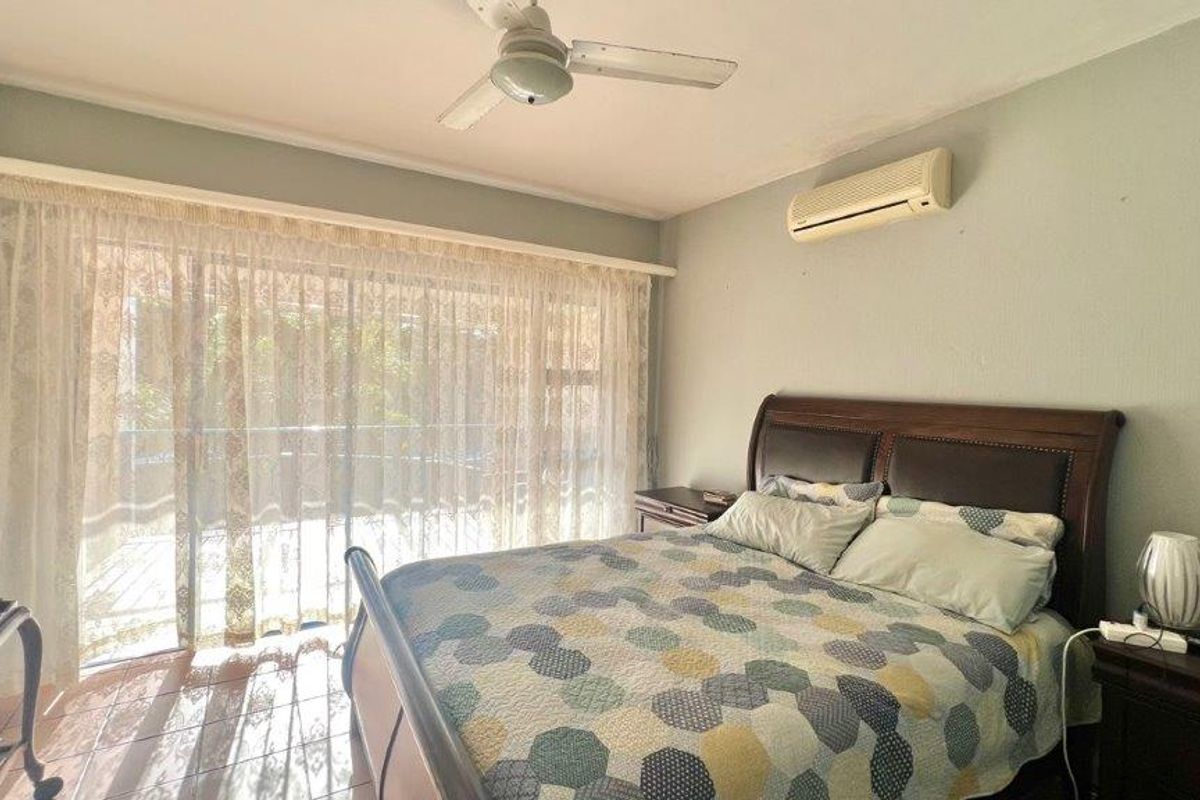 A bedroom featuring tiled flooring, a ceiling fan, a wall-mounted air conditioning unit, and a large sliding glass door providing access to the outdoors.
