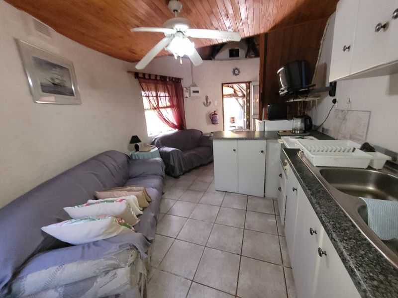 Open-plan living and kitchen area featuring tiled floors, timber ceiling, and functional cabinetry, offering a compact layout for daily living.