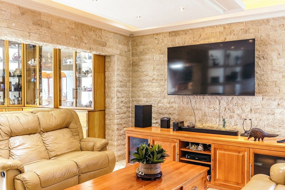 A cozy living room featuring a textured stone feature wall, recessed ceiling lighting, and built-in wooden display cabinetry.