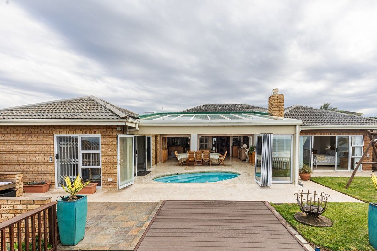 Rear view of the property featuring a covered patio, built-in swimming pool, brick facade, and tiled roof with access to interior living spaces.