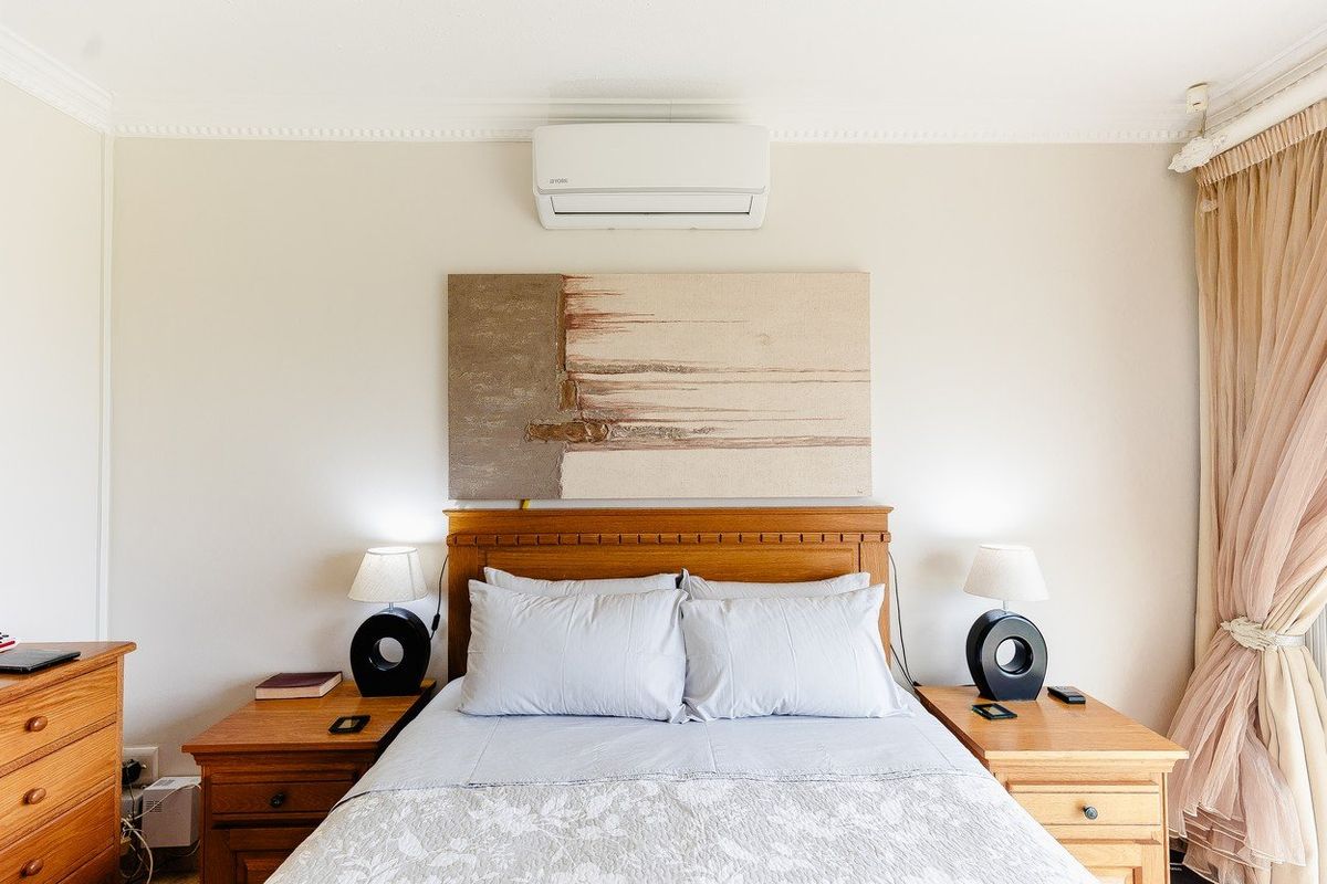 A well-maintained bedroom featuring a wall-mounted air conditioning unit, crown molding, and neutral wall finishes.