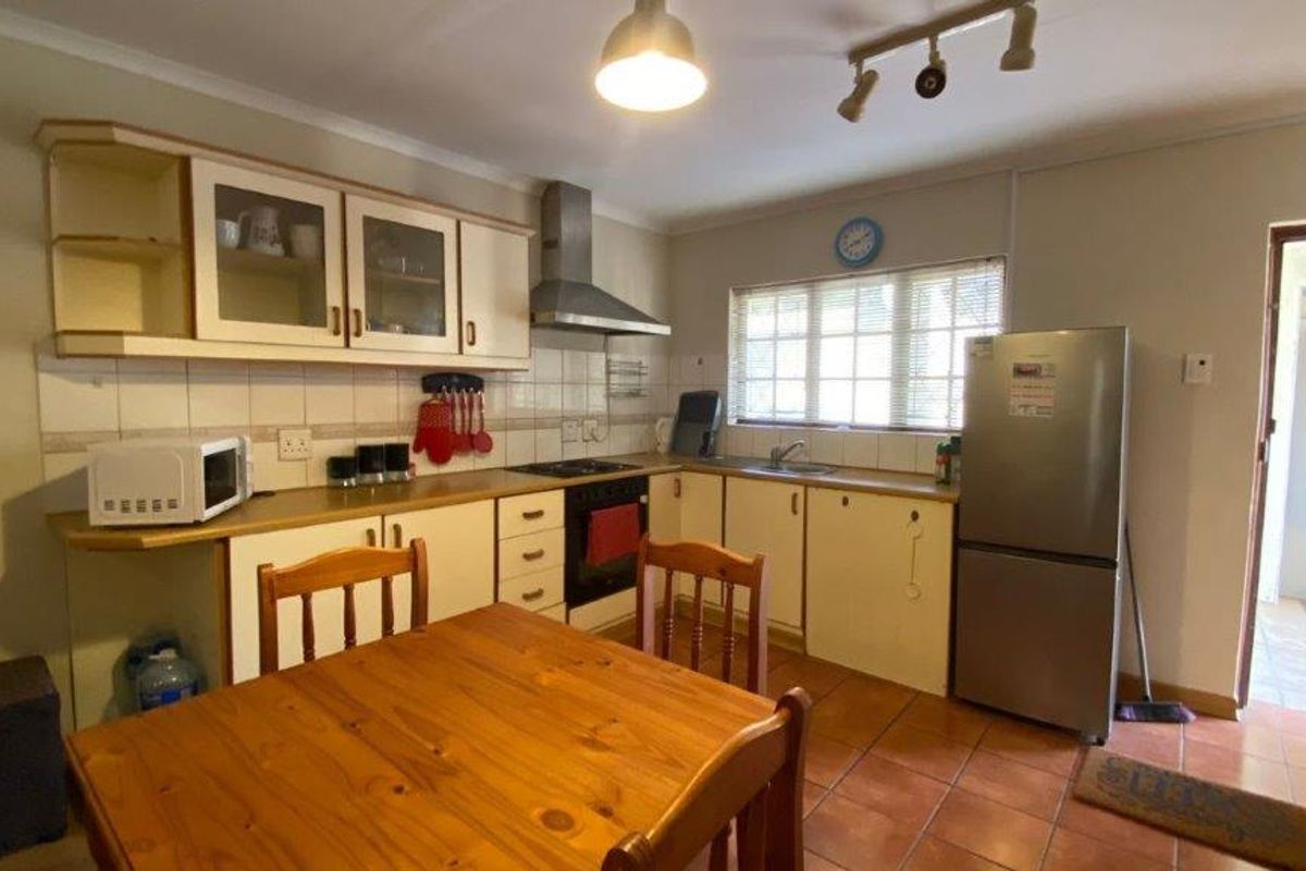 A functional kitchen featuring built-in cabinetry, laminate countertops, a stainless steel extractor fan, and tiled flooring with a practical layout.