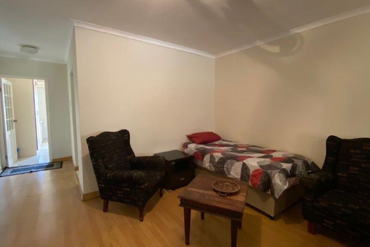 A bedroom featuring laminate flooring and coved ceilings, providing a functional living space with access to an adjoining hallway.