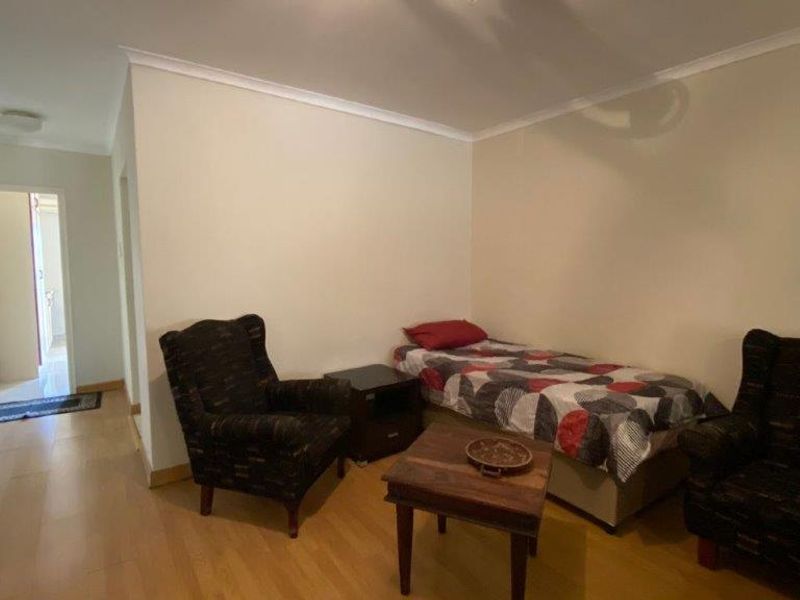 A bedroom featuring laminate flooring and coved ceilings, providing a functional living space with access to an adjoining hallway.