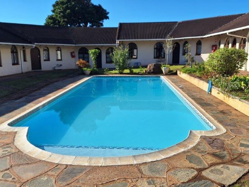 A well-maintained outdoor swimming pool area featuring stone paving and surrounded by the apartment building's exterior facade with arched windows.