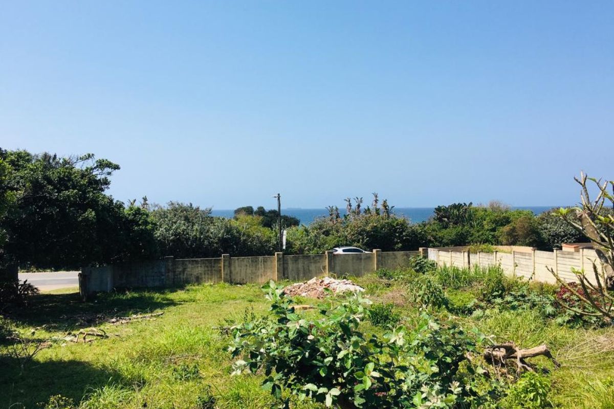 A vacant residential plot featuring a perimeter wall and a scenic coastal view, offering potential for future development.