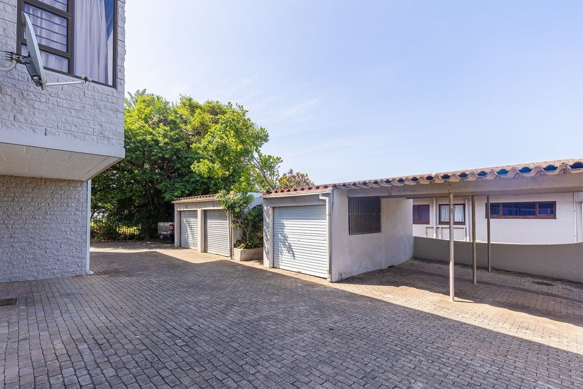 Exterior view of the apartment complex featuring a paved driveway, multiple garage units, and a covered carport area.