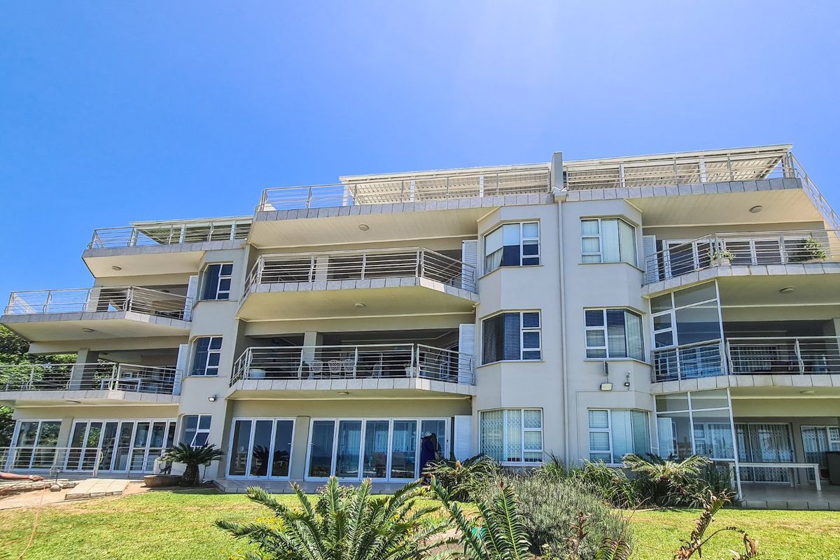 Rear elevation of a multi-story apartment building featuring multiple balconies with stainless steel railings, large sliding glass doors, and well-maintained garden areas.
