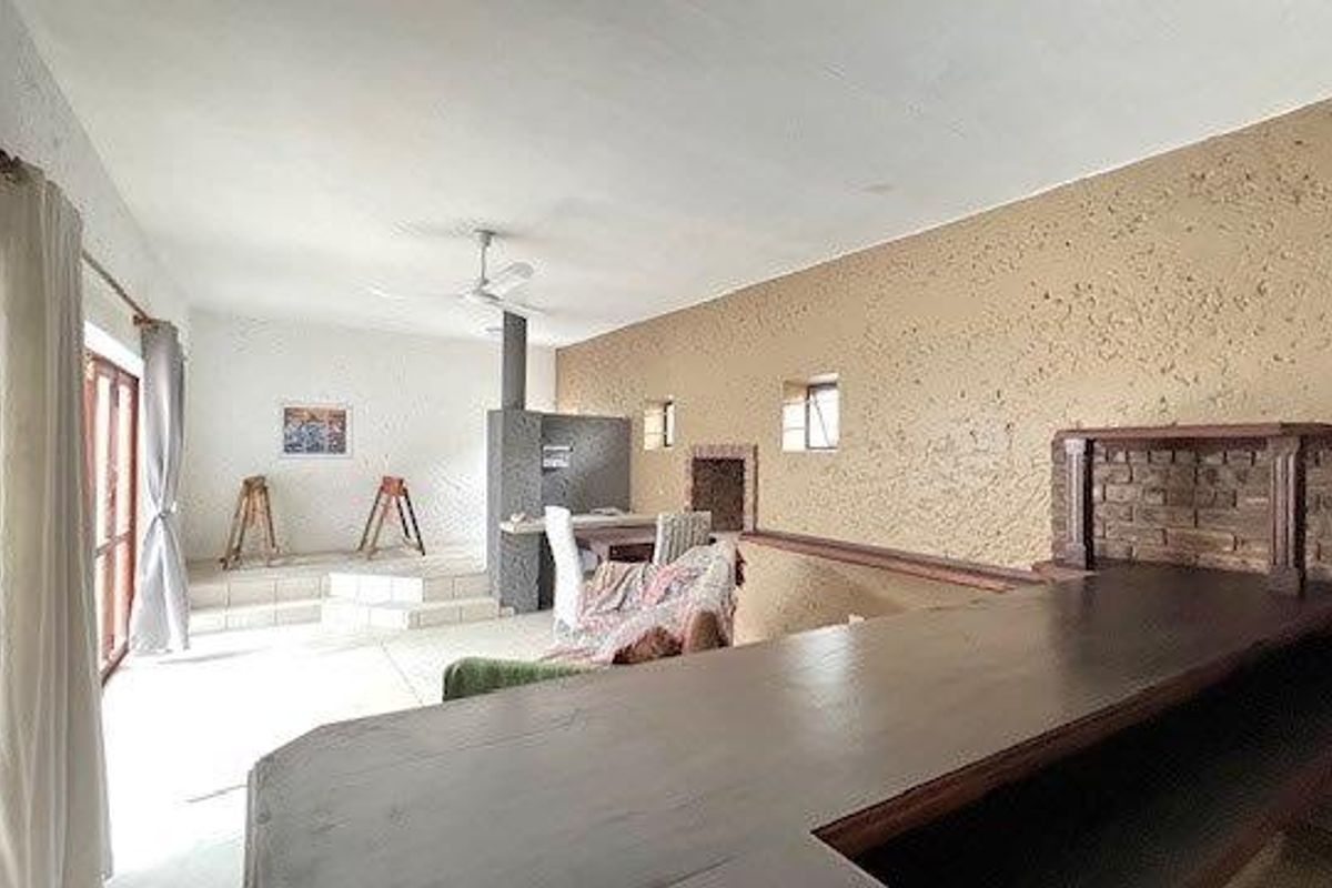 Spacious living area featuring a built-in bar, fireplace, and unique textured wall finishes with a raised platform section.
