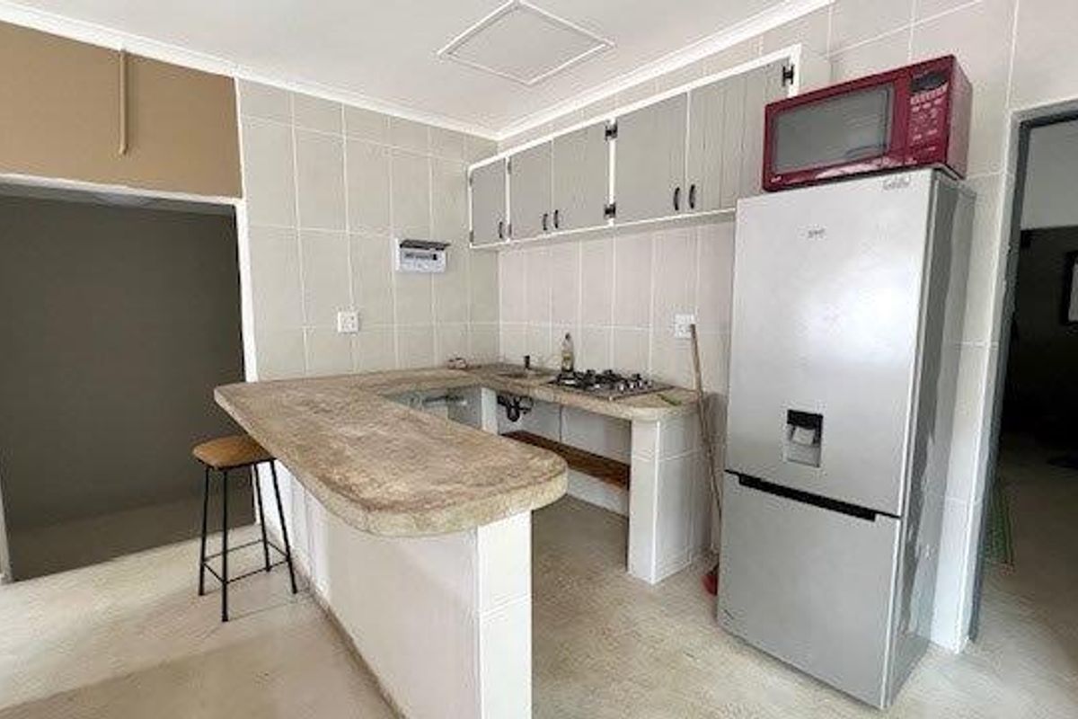 A functional kitchen featuring a breakfast counter, tiled splashbacks, and built-in cabinetry, requiring some finishing touches to complete the space.