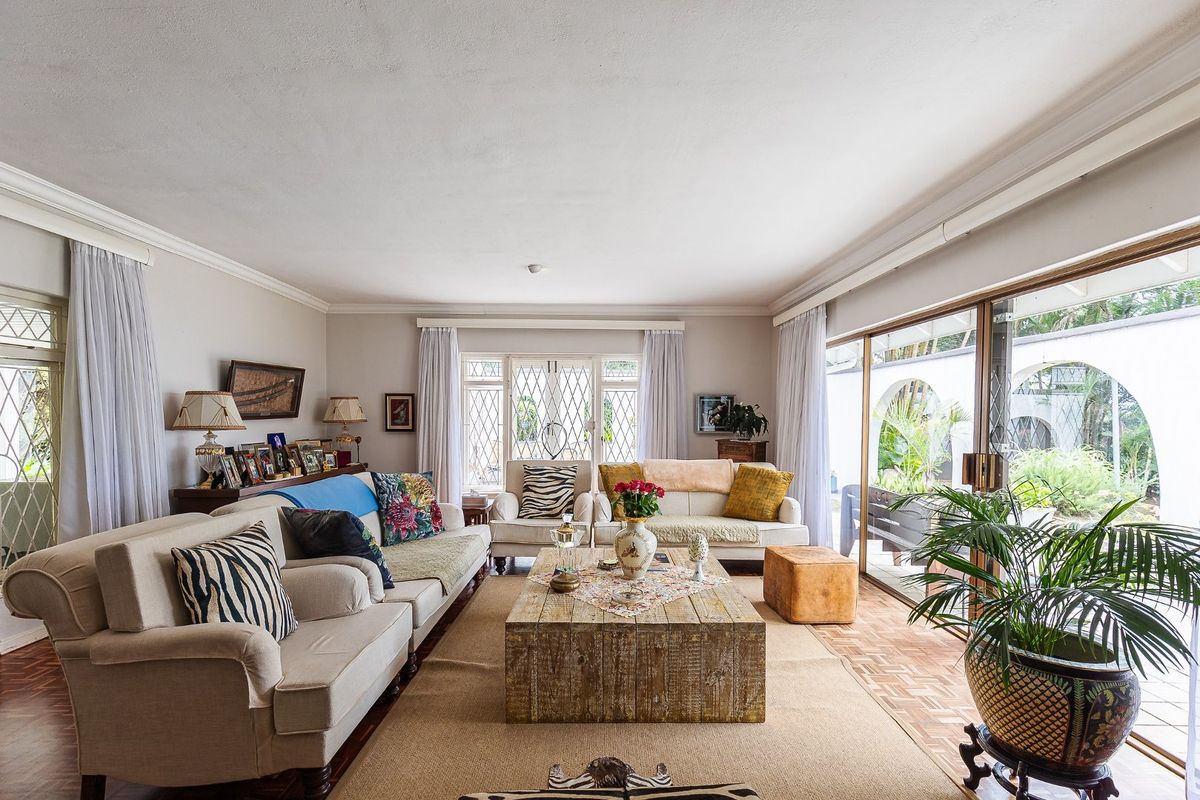 Spacious living room featuring classic parquet flooring, crown molding, and large sliding glass doors that provide seamless access to the outdoor patio area.