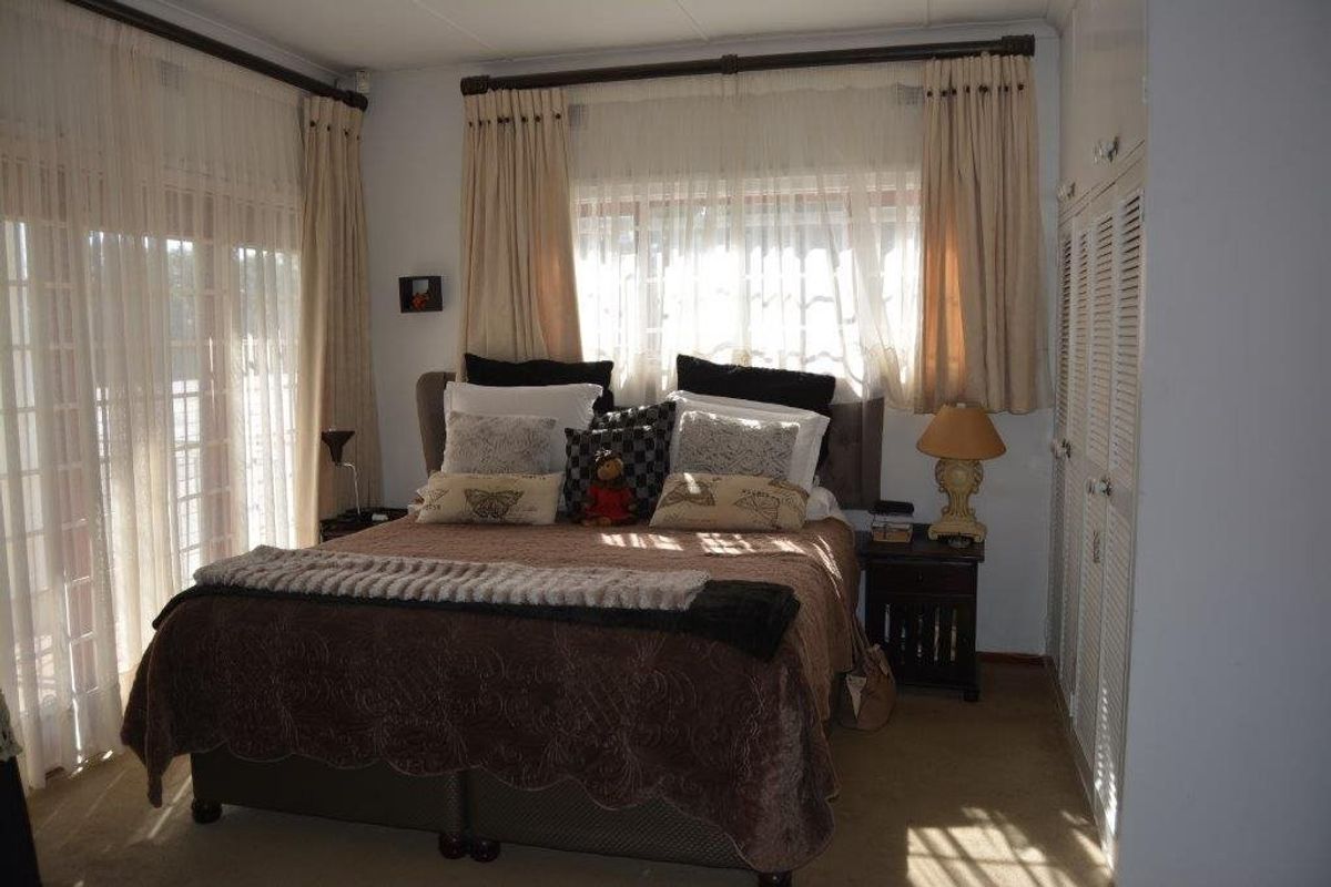 A comfortable bedroom featuring built-in cupboards, neutral carpeting, and large sliding glass doors that provide ample natural light.