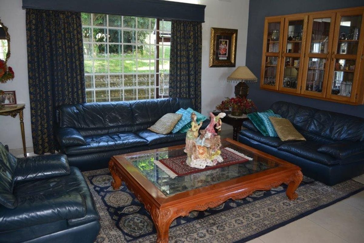 A comfortable living room featuring built-in wooden display cabinetry, large windows providing natural light, and neutral tiled flooring.