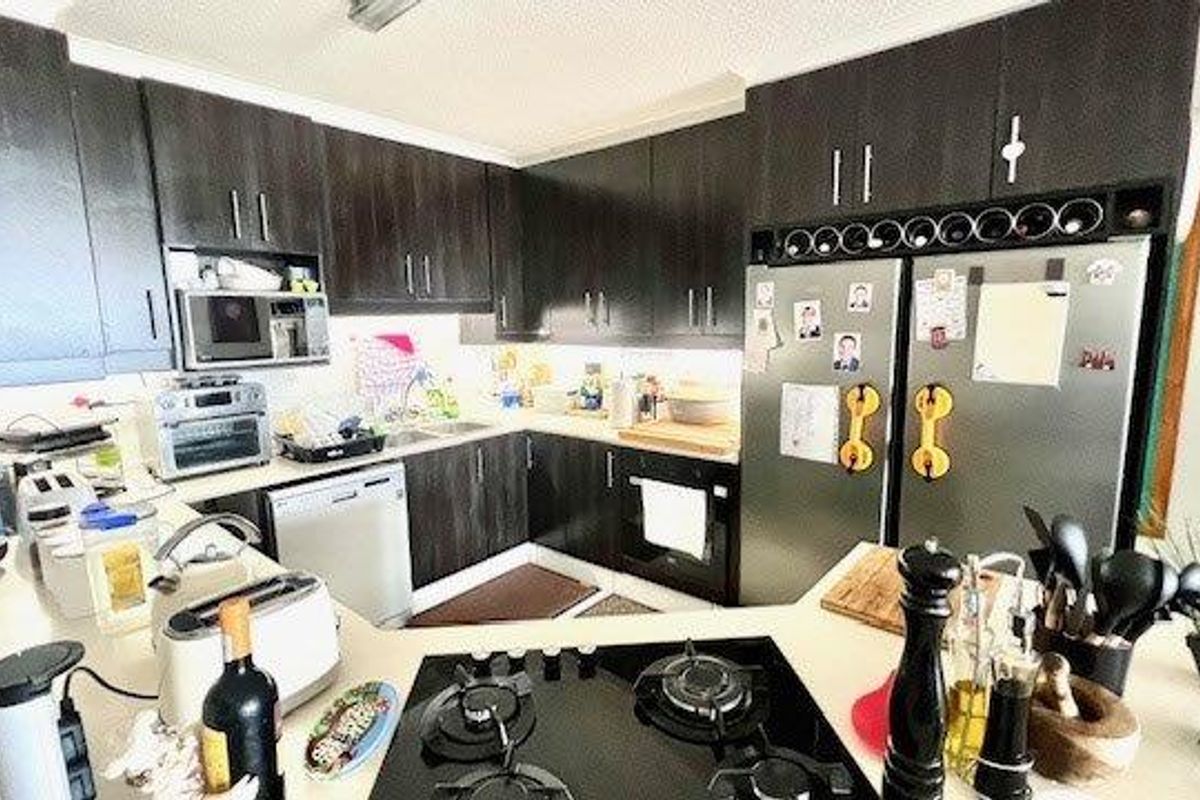 A functional kitchen featuring dark wood cabinetry, stone countertops, a built-in oven, and a gas cooktop, providing ample storage and workspace.