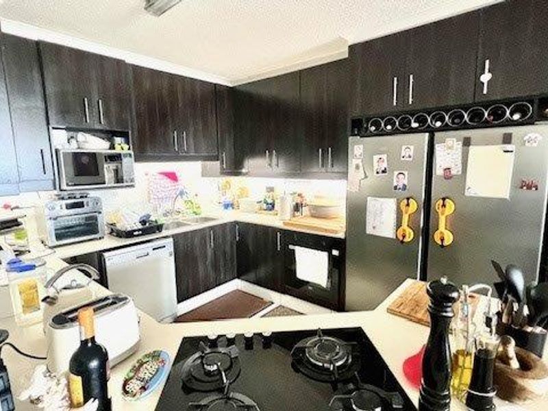 A functional kitchen featuring dark wood cabinetry, stone countertops, a built-in oven, and a gas cooktop, providing ample storage and workspace.