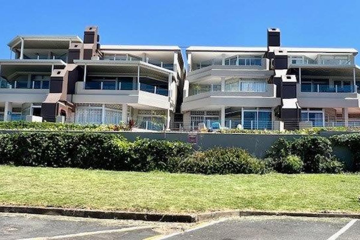 Rear elevation of a multi-story apartment complex featuring private balconies, large sliding glass doors, and integrated chimneys.