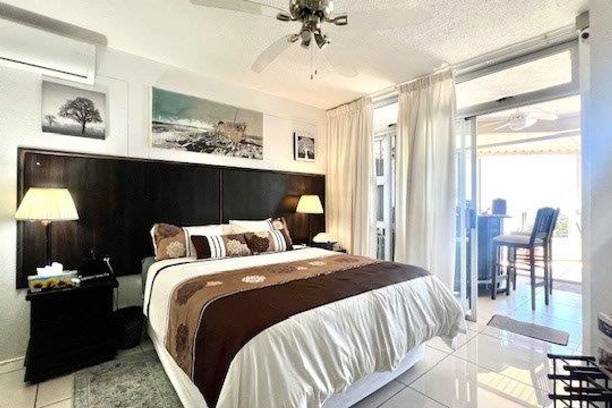 A well-maintained bedroom featuring tiled floors, a ceiling fan, split-system air conditioning, and direct access to a private balcony through sliding glass doors.