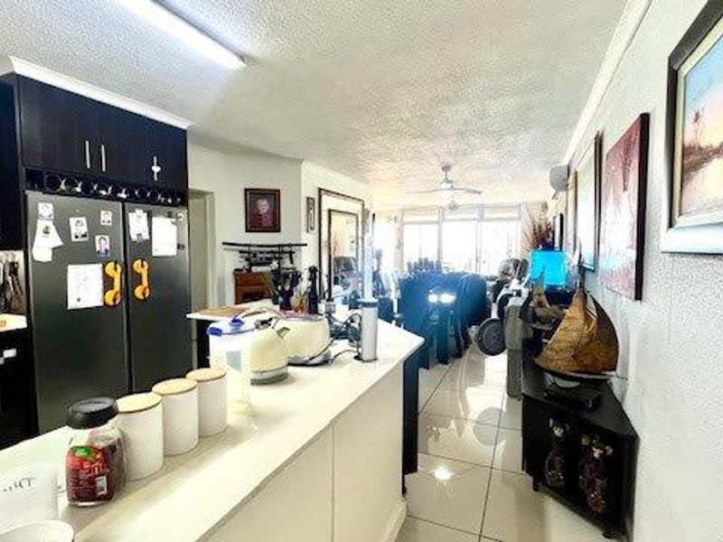 Open-plan living and kitchen area featuring dark cabinetry, a central island, and tiled flooring, creating a functional and connected living space.