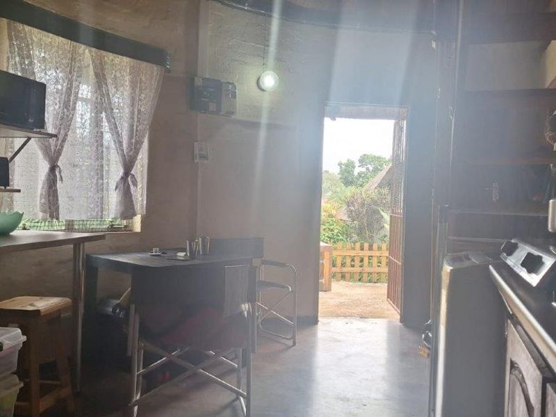 An open-plan living area featuring exposed brick walls, a staircase, and direct access to an outdoor patio area.