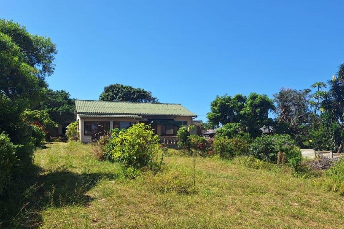 A view of the rear elevation of the house featuring a pitched roof and a large, established garden area.