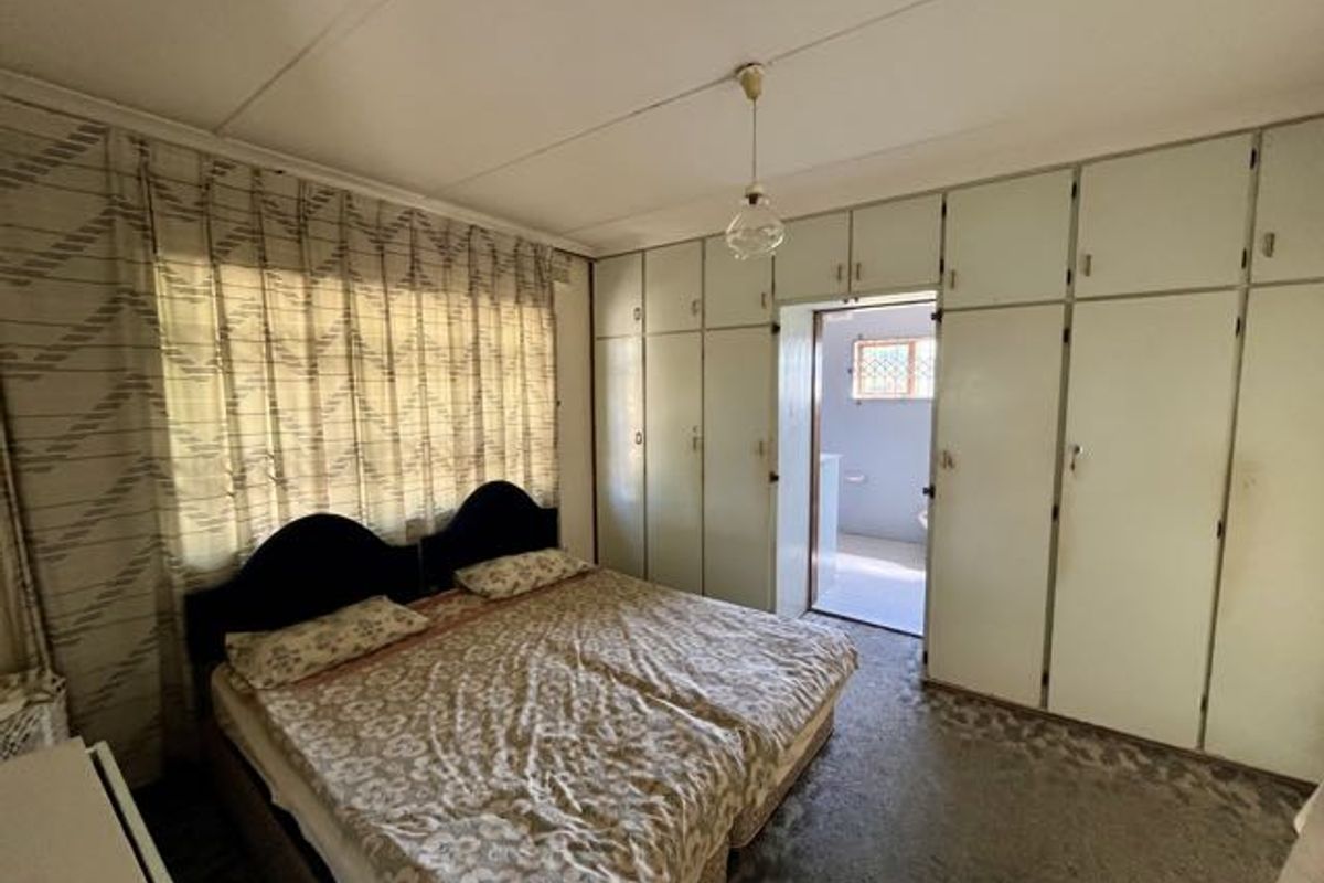 Bedroom featuring extensive built-in cupboards, carpeted flooring, and direct access to an en-suite bathroom.