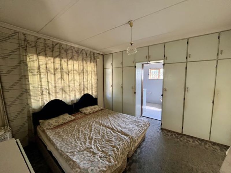 Bedroom featuring extensive built-in cupboards, carpeted flooring, and direct access to an en-suite bathroom.